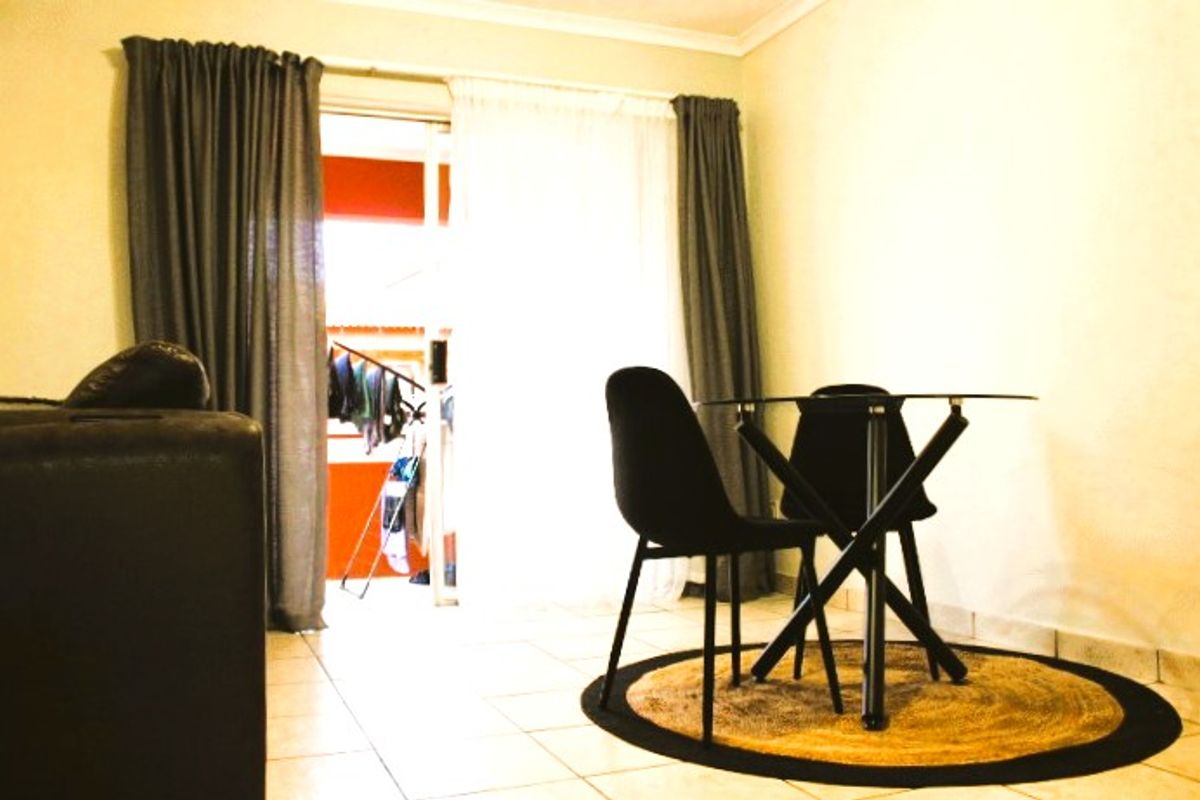 A living area featuring tiled flooring and a sliding glass door providing access to an outdoor balcony space.