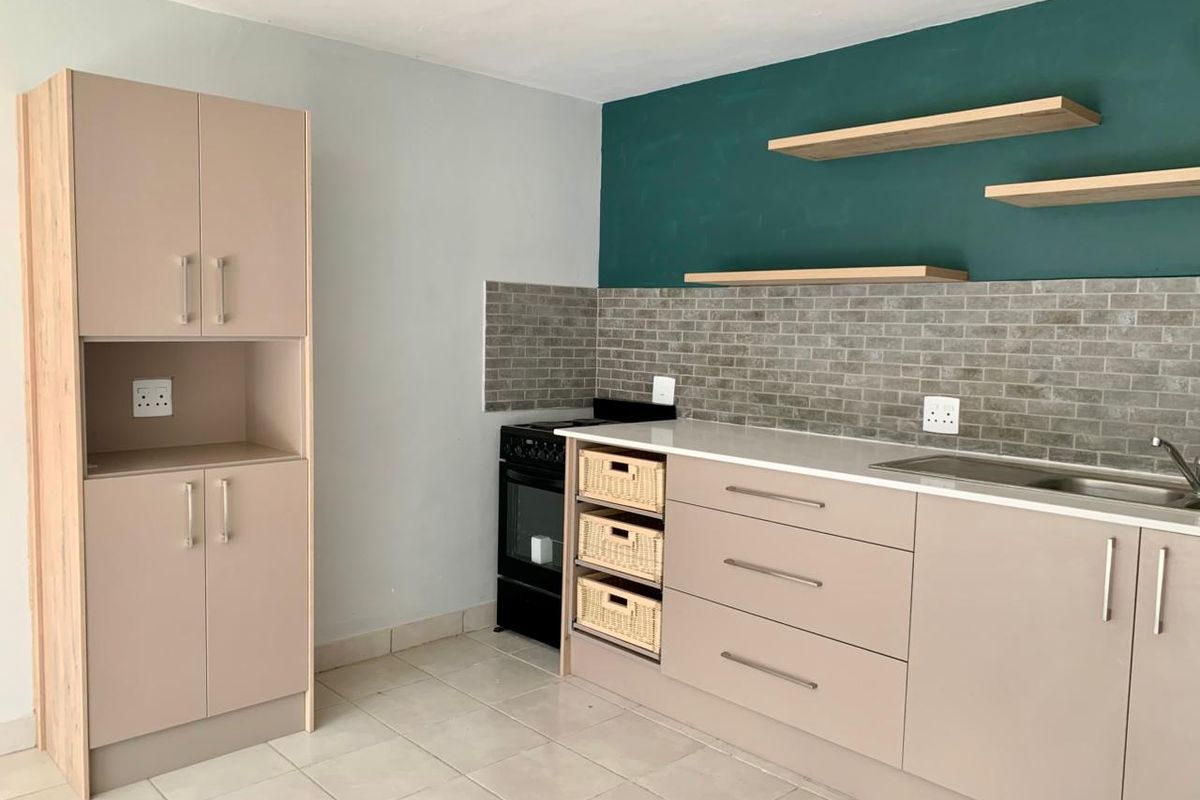 Modern kitchen featuring neutral cabinetry, a subway tile backsplash, floating timber shelves, and a freestanding stove.