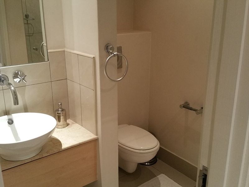 A compact bathroom featuring a modern vessel sink with wall-mounted tapware, a stone vanity top, and a separate toilet area.