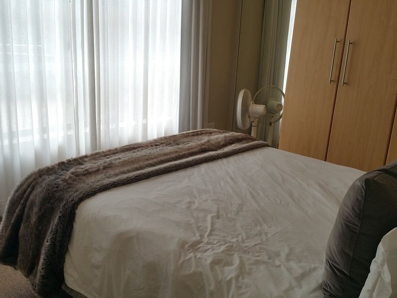 A bedroom featuring neutral carpet flooring, floor-to-ceiling sheer curtains, and a built-in wooden wardrobe.