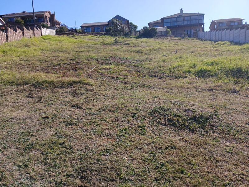A vacant residential plot featuring a sloped landscape with established boundary walls, situated in a developed neighborhood.