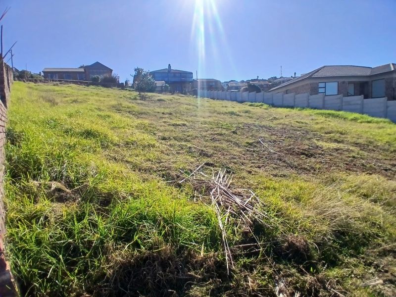 A vacant residential plot featuring a gentle slope and a precast concrete boundary wall, situated in an established neighbourhood.