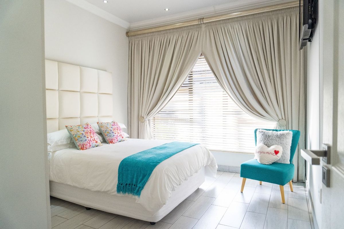 A bright and well-maintained bedroom featuring tiled flooring, recessed ceiling lighting, and large window treatments.