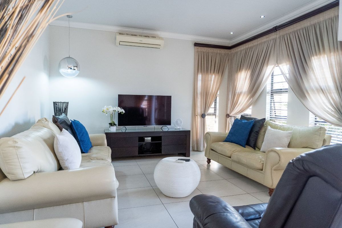 A comfortable living room featuring tiled flooring, recessed ceiling lighting, and a wall-mounted air conditioning unit.