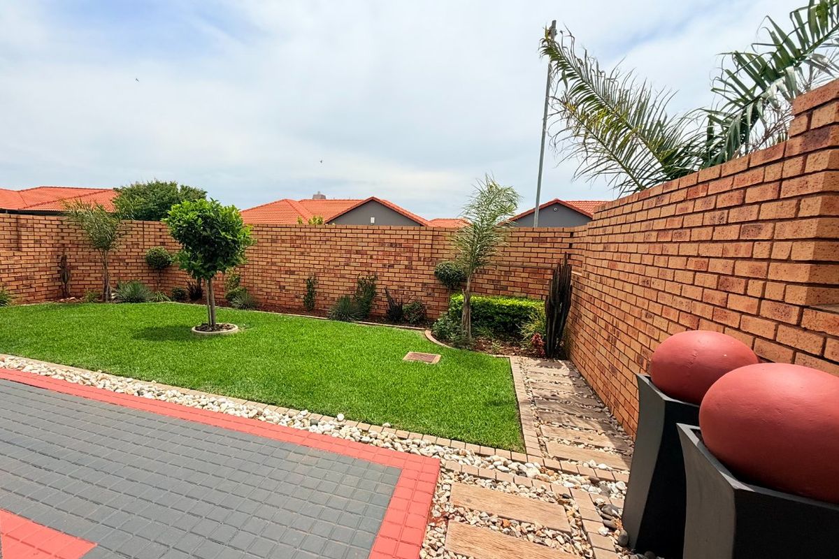 A well-maintained rear garden featuring a neat lawn, brick boundary walls, and a paved patio area, providing a clean and private outdoor space.