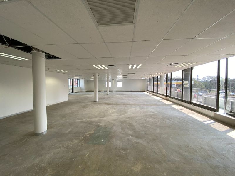 Spacious open-plan commercial office space featuring large windows, suspended ceilings, and structural columns, currently in a shell condition ready for fit-out.