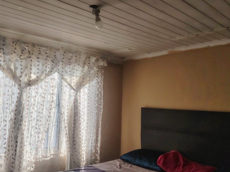 A bedroom featuring a timber tongue and groove ceiling and natural light through the window.