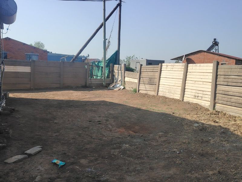 A spacious, undeveloped backyard area enclosed by precast concrete walling, offering a blank canvas for landscaping and outdoor improvement projects.