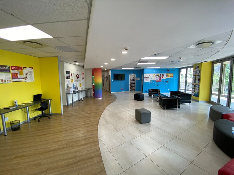 Spacious open-plan commercial reception or waiting area featuring a mix of tiled and wood-look flooring, recessed lighting, and large sliding glass doors.