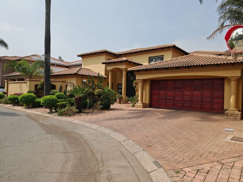 Front elevation of a Mediterranean-style house featuring a brick-paved driveway, double garage, and covered entrance with decorative columns.