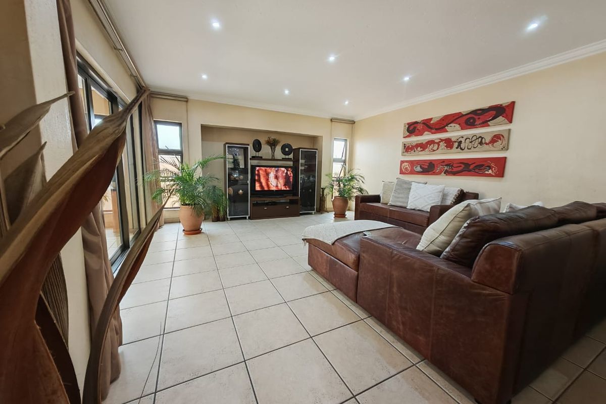 Spacious living room featuring large format floor tiles, recessed downlighting, and a built-in media alcove with direct access to an outdoor patio area.
