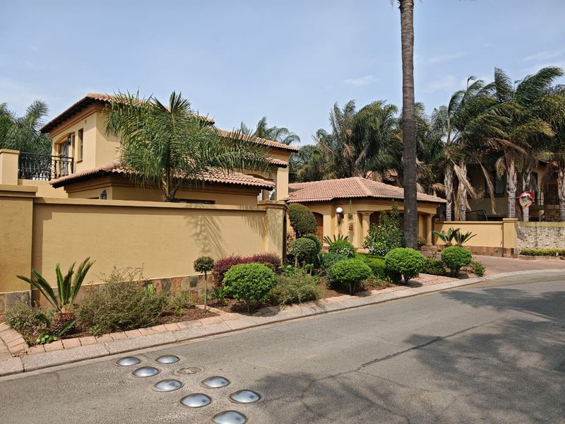 A well-maintained residential property featuring a Mediterranean-style facade with terracotta roof tiles, stone accents, and a neatly landscaped front garden.