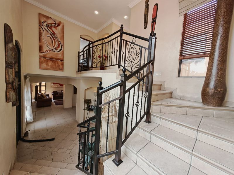 Spacious entrance hall featuring a tiled staircase with decorative wrought iron balustrades and an open-plan layout leading to the living area.