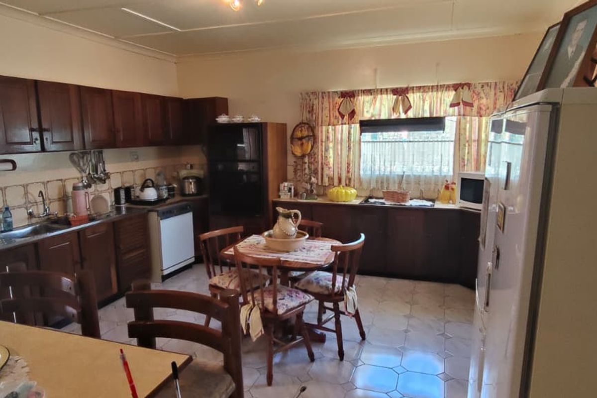 A functional kitchen featuring traditional wooden cabinetry, tiled backsplash, and tiled flooring, offering a classic layout with integrated cooking and wash-up areas.