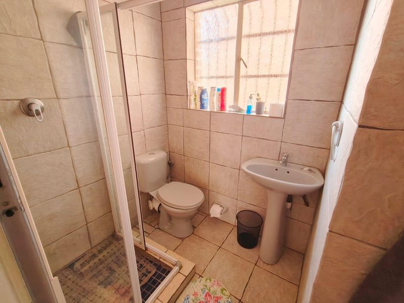 A compact bathroom featuring a pedestal sink, toilet, and a glass-enclosed shower with floor-to-ceiling wall tiling.