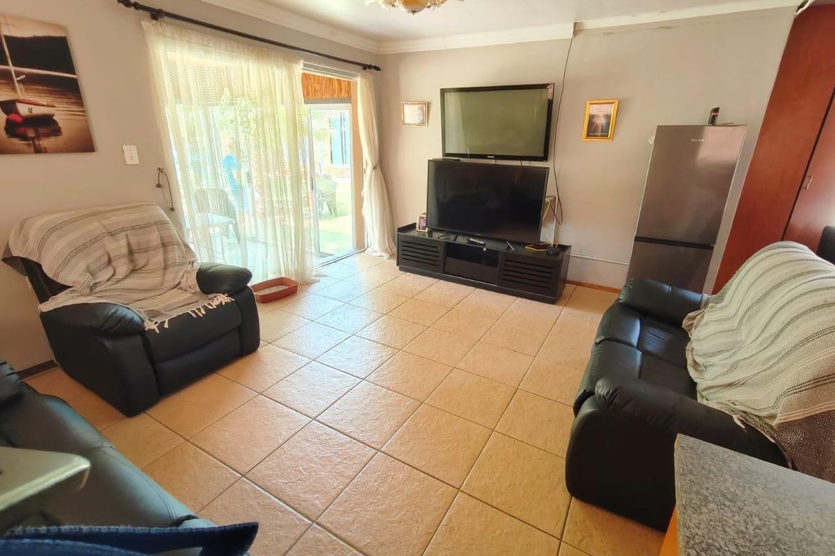 A living room featuring tiled flooring and a sliding glass door providing access to the outdoor area, with neutral wall finishes.