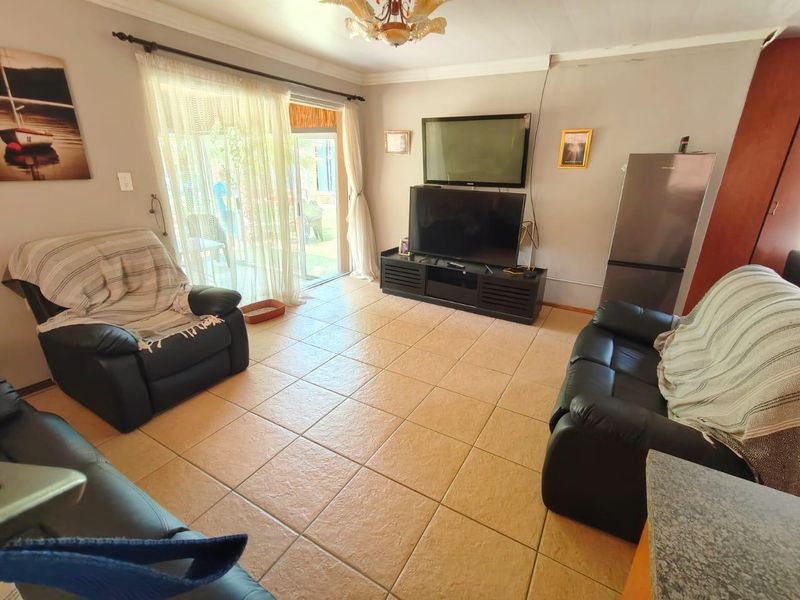 A living room featuring tiled flooring and a sliding glass door providing access to the outdoor area, with neutral wall finishes.