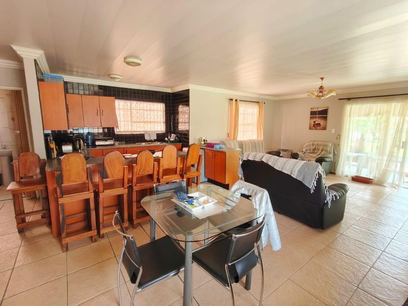 Open plan living and kitchen area featuring tiled flooring, a breakfast bar, and functional kitchen cabinetry with a tiled backsplash.