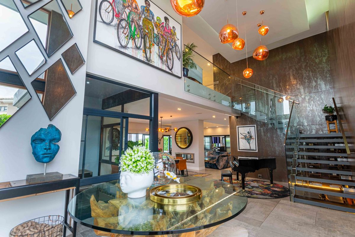 Spacious double-volume living area featuring a modern glass staircase, high-end finishes, and elegant lighting, creating a sophisticated and open atmosphere.
