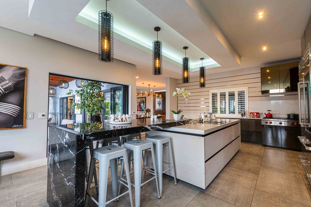 Modern, high-end kitchen featuring a large stone-topped island, integrated appliances, recessed ceiling lighting, and sleek cabinetry with a seamless open-plan layout.