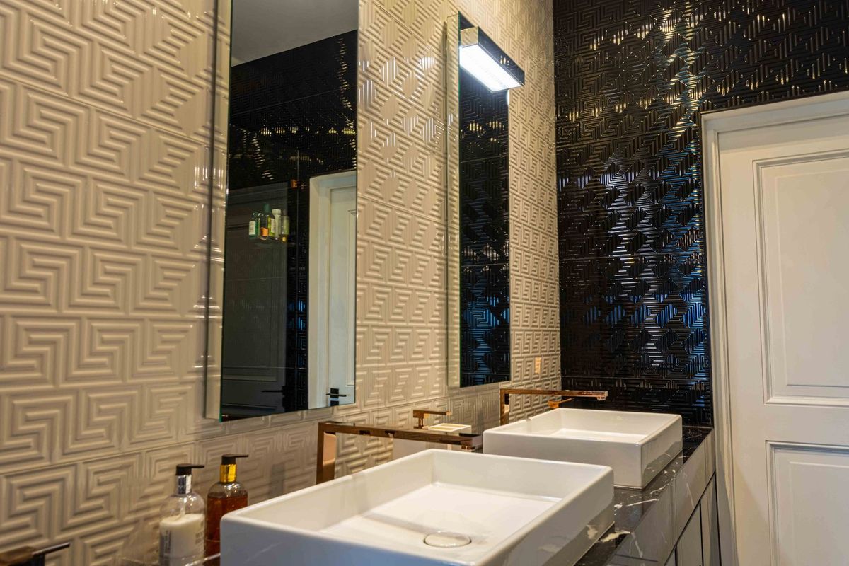 Modern bathroom featuring a double vanity with vessel sinks, wall-mounted faucets, and striking high-contrast textured wall tiling.