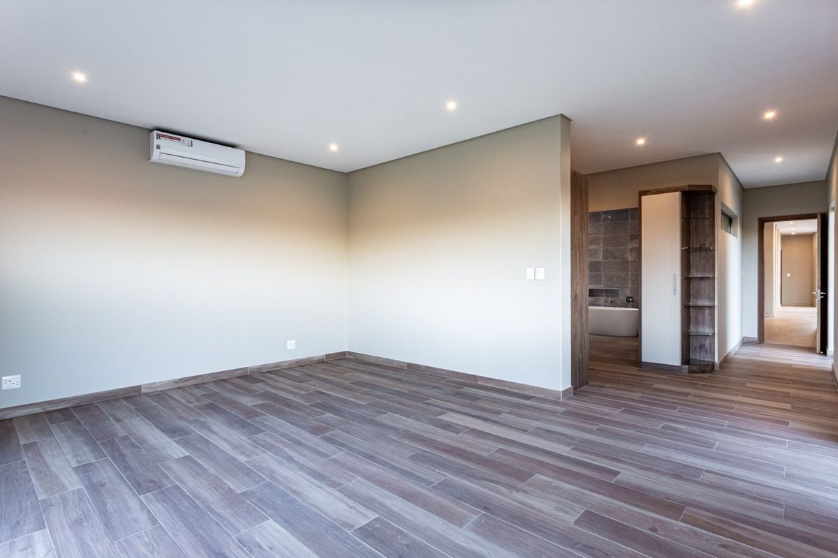 Spacious bedroom featuring wood-look tile flooring, recessed lighting, an air conditioning unit, and direct access to an en-suite bathroom.