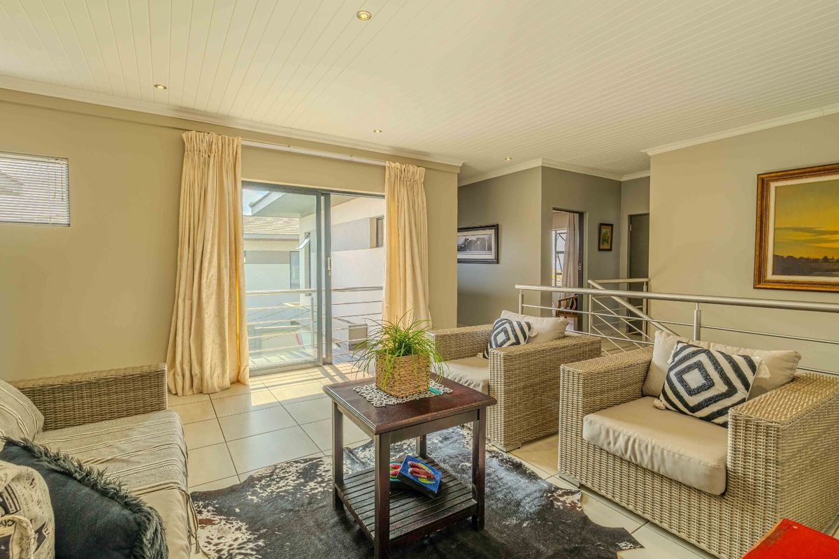 A bright living area featuring tiled flooring, a tongue-and-groove ceiling, and sliding glass doors that open onto a balcony.