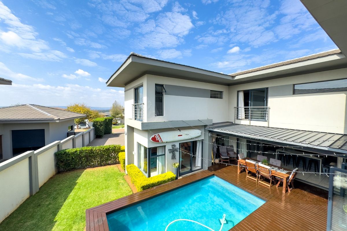 A modern two-story home featuring a swimming pool, timber decking, and a covered patio area, perfect for outdoor entertaining.