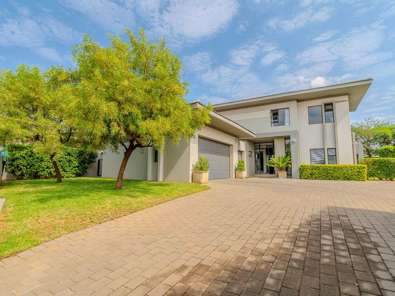Modern double-story residential home featuring a paved driveway, integrated garage, and well-maintained front garden area.