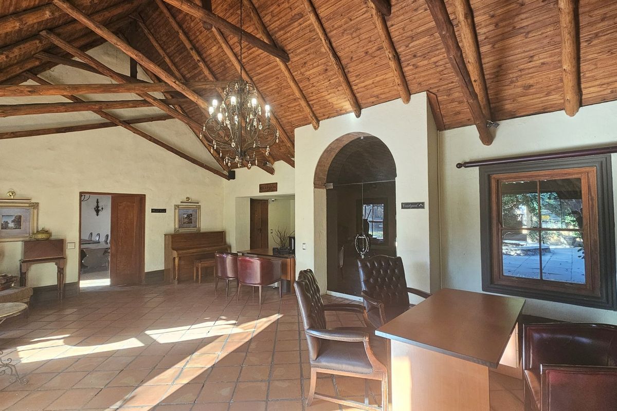 Spacious commercial reception area featuring high vaulted timber ceilings with exposed trusses, terracotta flooring, and a classic wrought iron chandelier.