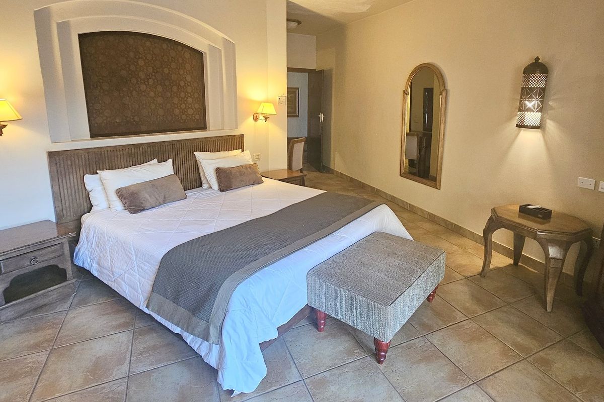 A well-maintained bedroom featuring tiled flooring, a decorative recessed wall niche, and warm wall-mounted lighting fixtures.