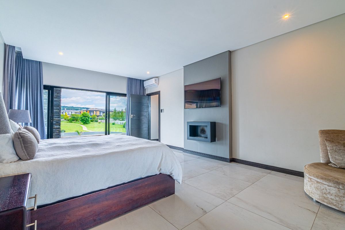 Spacious bedroom featuring large sliding glass doors, tiled flooring, a modern wall-mounted fireplace, and integrated air conditioning unit.