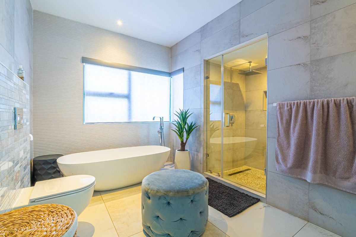 Modern bathroom featuring a freestanding bathtub, a glass-enclosed walk-in shower with rainfall showerhead, and contemporary wall and floor tiling.
