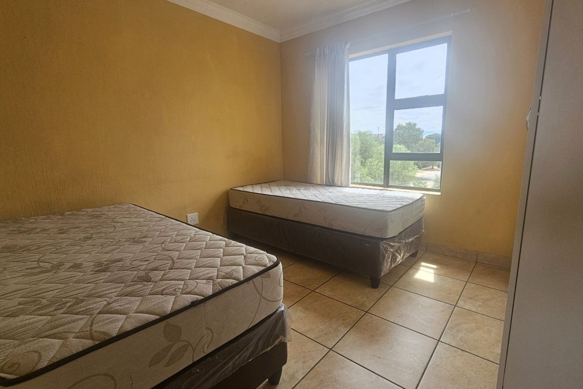A bedroom featuring tiled flooring, yellow painted walls, and a large window providing natural light.