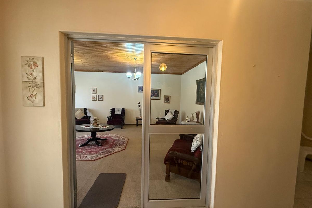 A view through a sliding glass door into a living room featuring a timber-clad ceiling and carpeted flooring.