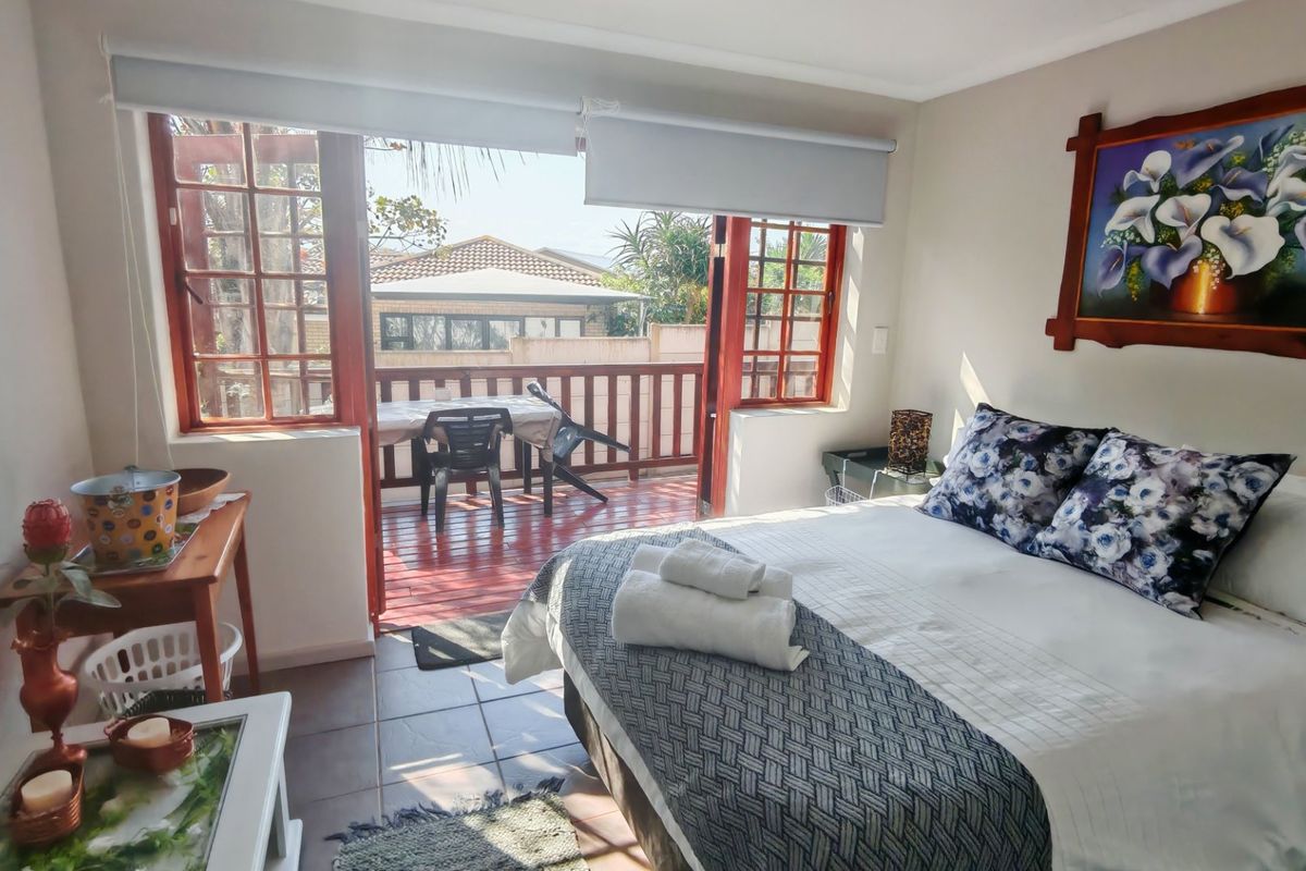 A bedroom featuring tiled flooring and timber-framed glass doors that open onto a private balcony.