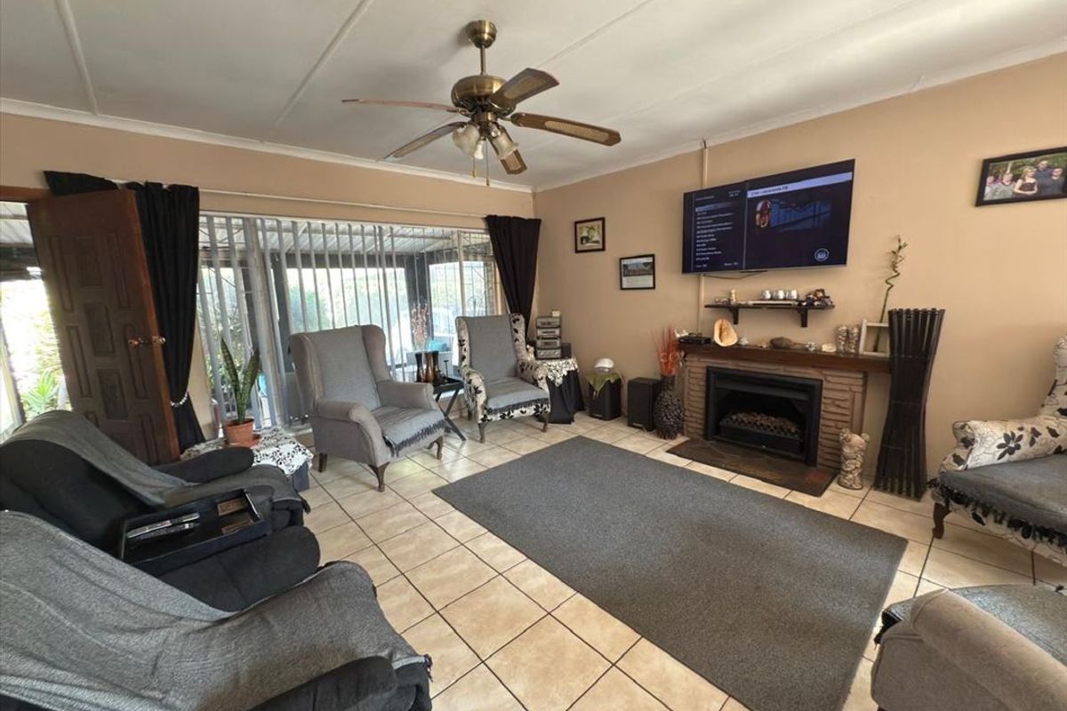 A living room featuring a brick fireplace, tiled flooring, and a ceiling fan, with direct access to an outdoor patio area.