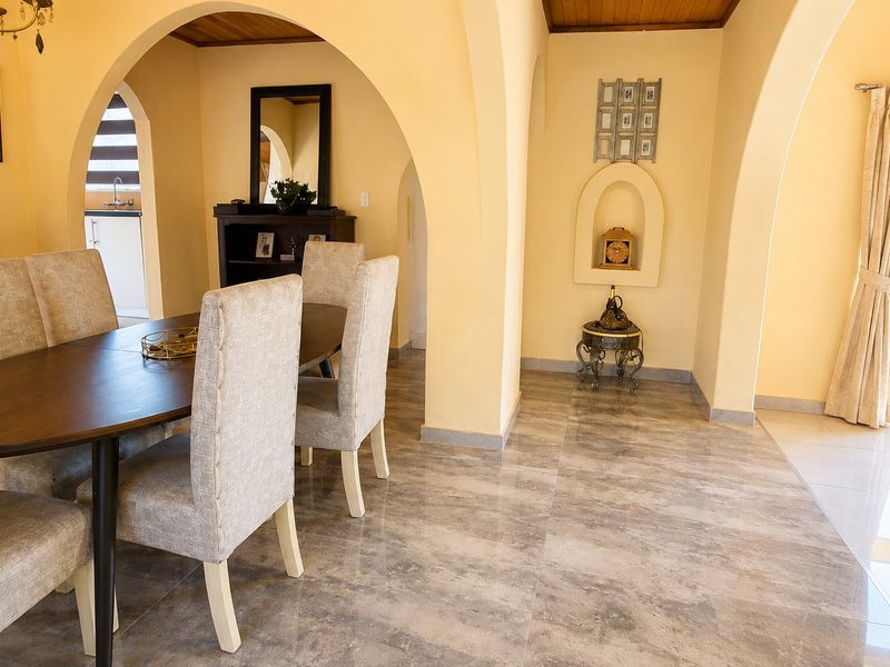 Dining area featuring elegant arched doorways, polished tile flooring, and a recessed wall niche, with direct access to the outdoor garden area.