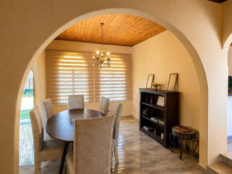 A dining room featuring a timber ceiling, tiled flooring, and a distinctive arched entryway, creating a warm and inviting atmosphere.