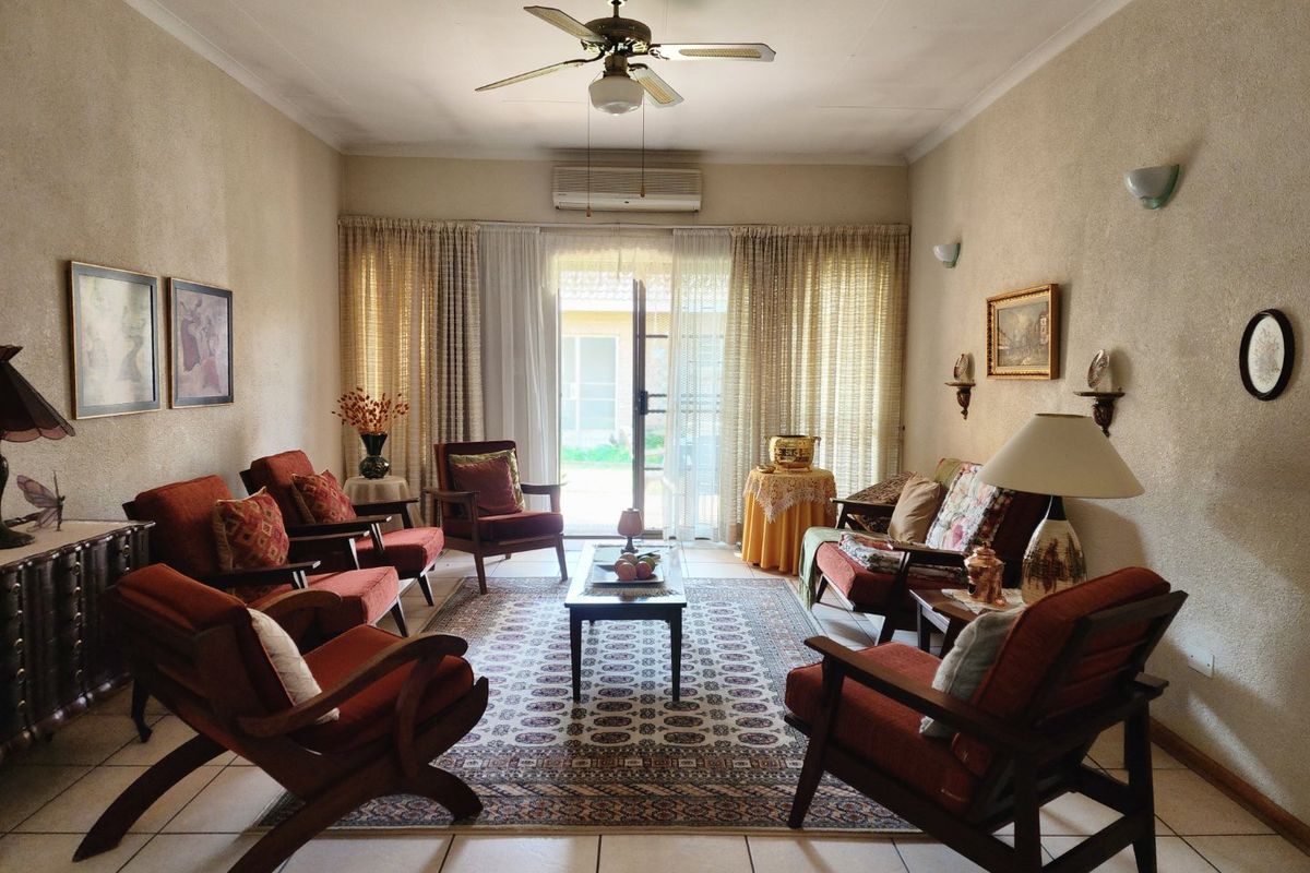 A spacious living room featuring tiled flooring, a ceiling fan, and a split-system air conditioner, with direct access to an outdoor area via sliding doors.