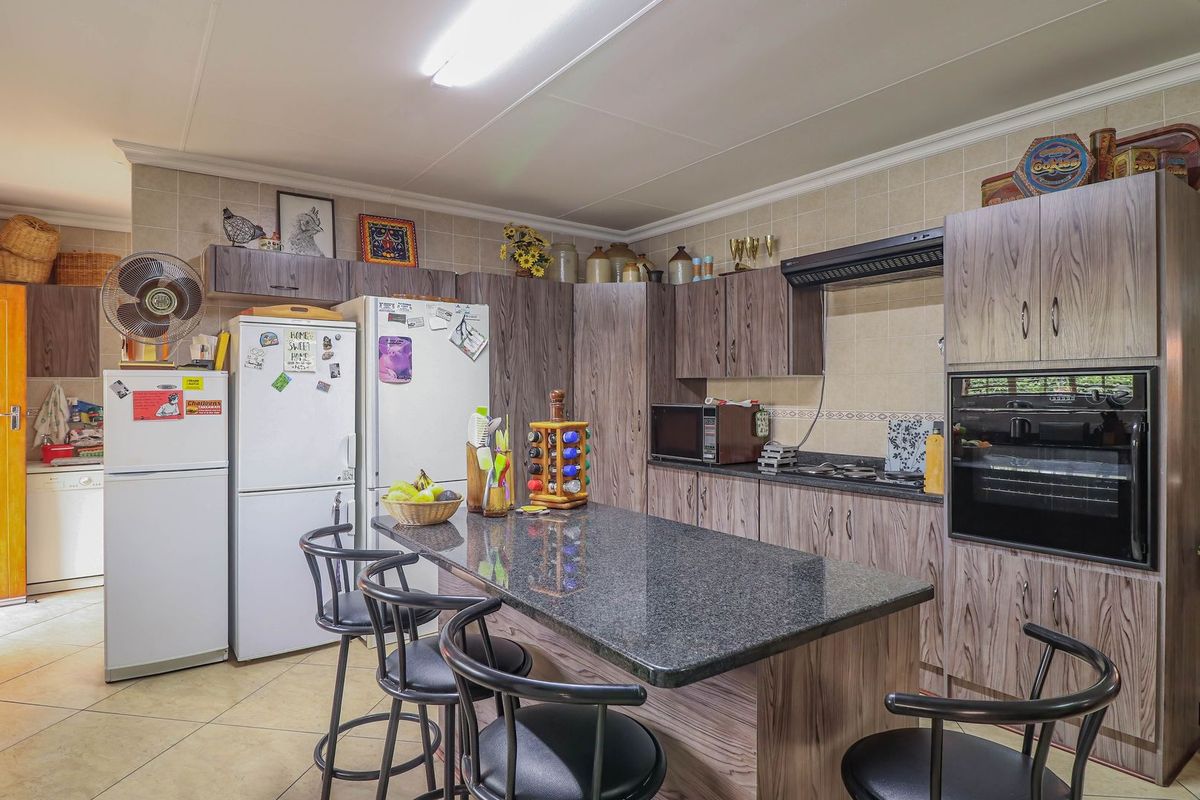 A functional kitchen featuring wood-grain cabinetry, granite countertops, a central island, built-in oven, and tiled flooring.