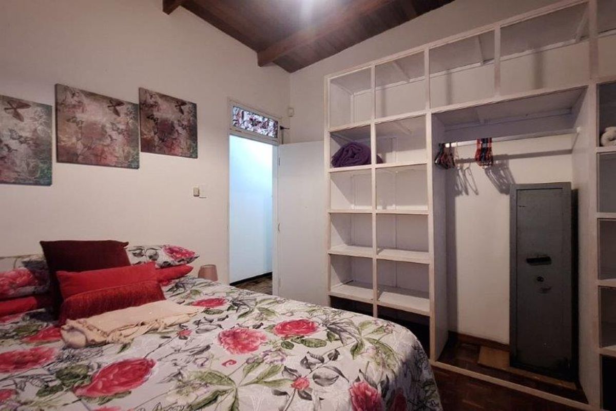 Bedroom featuring exposed timber ceiling beams, parquet flooring, and extensive built-in shelving units for storage.