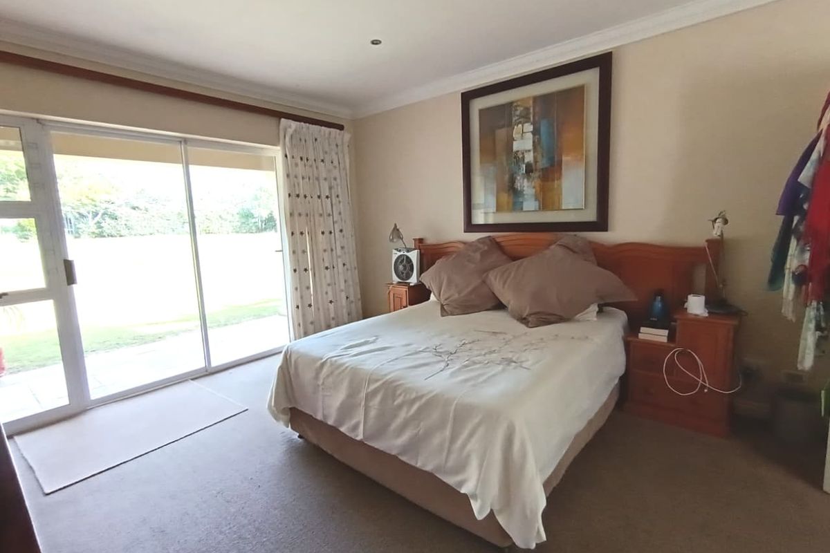 Spacious bedroom featuring neutral carpeting, a ceiling fan, and large sliding glass doors providing direct access to the outdoor area.