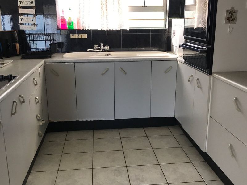A functional U-shaped kitchen featuring white cabinetry, a double wall oven, tiled backsplash, and ceramic floor tiles.