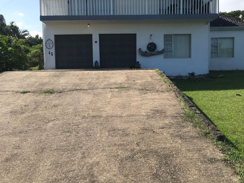 Front elevation of a two-story house featuring a double garage, concrete driveway, and an upper-level balcony with white railings.