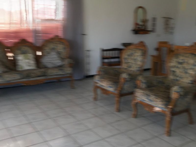 A living room area featuring tiled flooring and a ceiling fan, providing a functional space for relaxation.