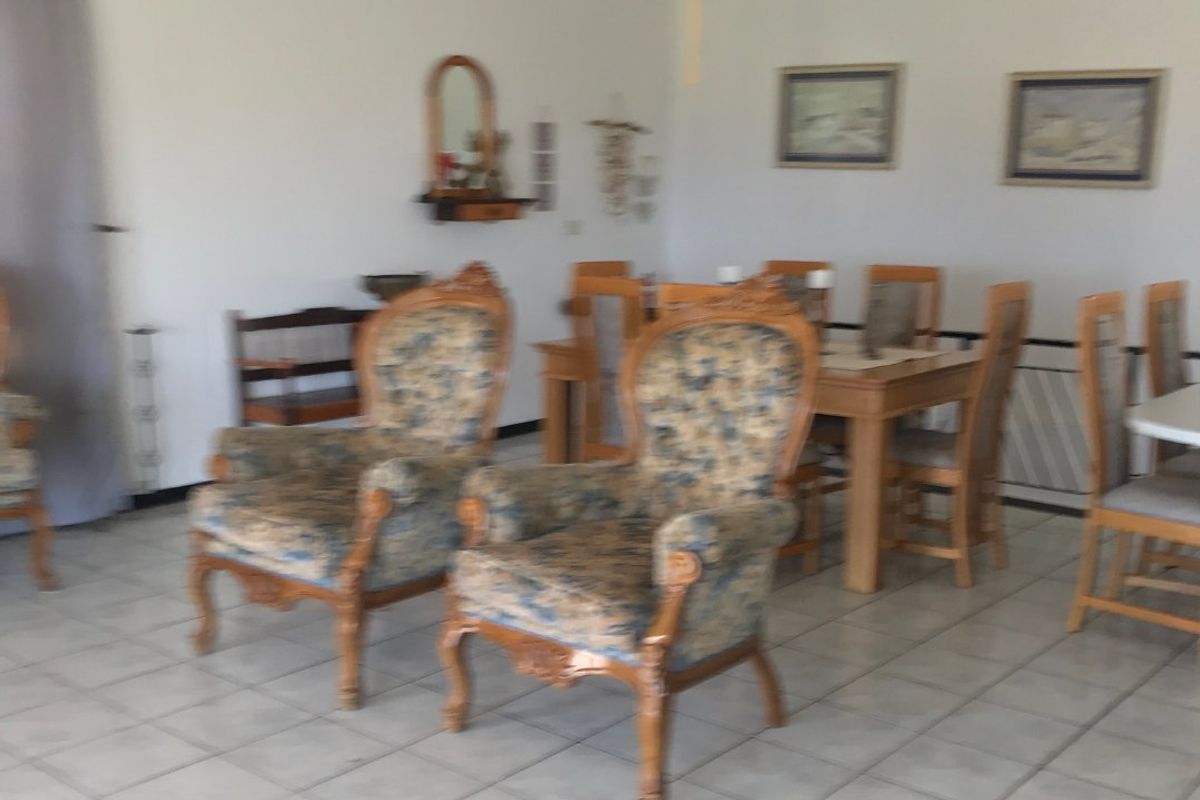 A spacious living and dining area featuring neutral tiled flooring and a ceiling fan, offering a functional layout for family living.