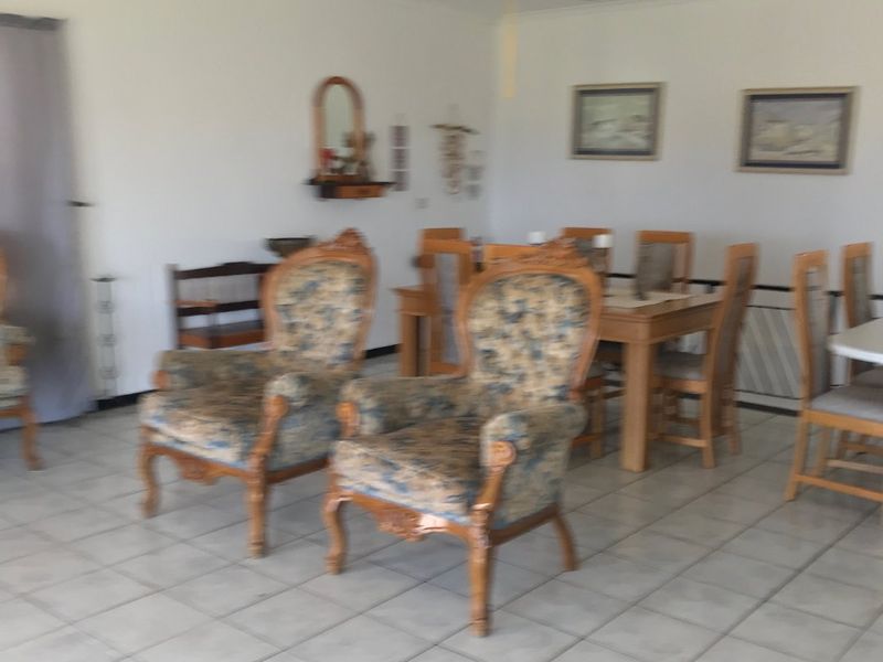 A spacious living and dining area featuring neutral tiled flooring and a ceiling fan, offering a functional layout for family living.