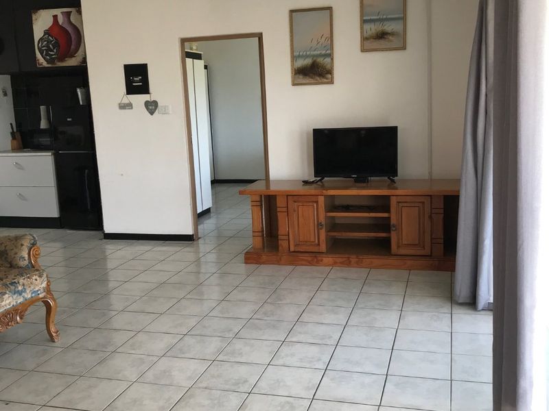 Open plan living area featuring tiled flooring and a partial view of the kitchen cabinetry.