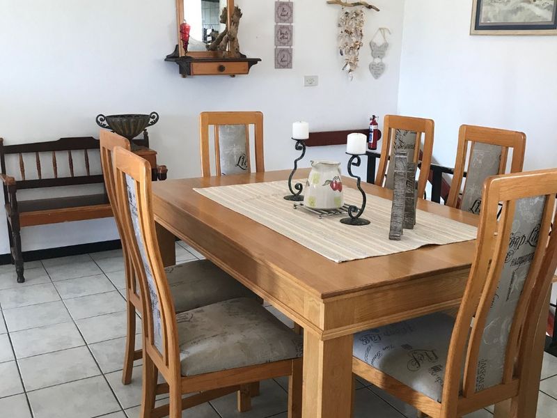 A functional dining area featuring neutral ceramic floor tiles and a simple, clean layout suitable for family meals.